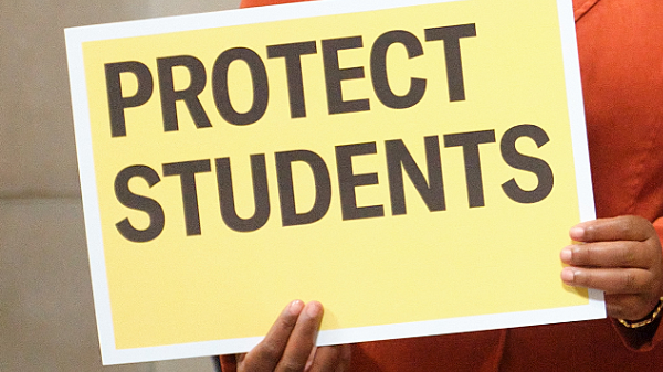 A press conference attendee holds a sign reading Protect Students at the Nebraska State Capitol.