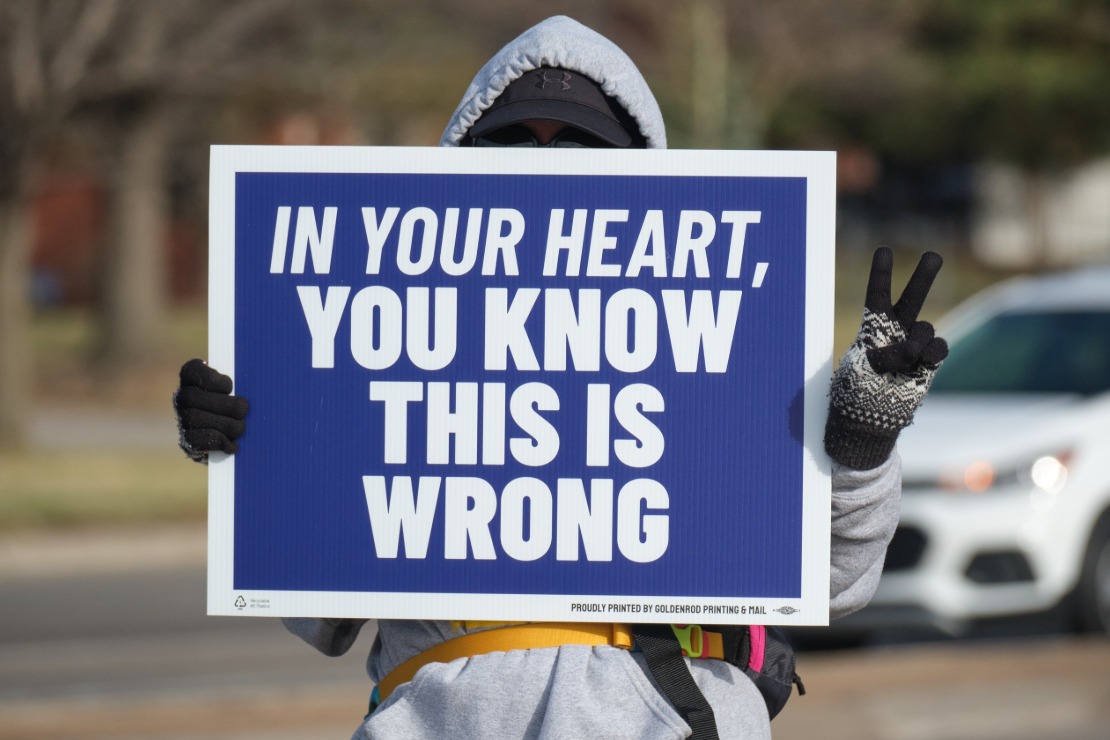 A protester in Lincoln holds a sign reading "In your heart, you know this is wrong."