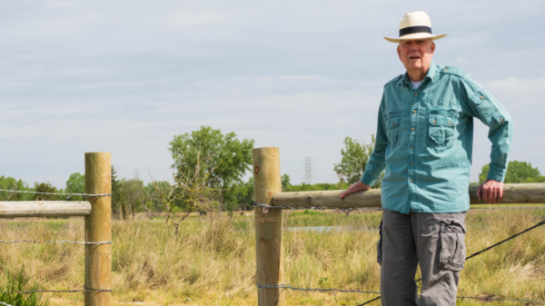 W. Don Nelson leans against a fence by Lincoln's Saline Wetlands.
