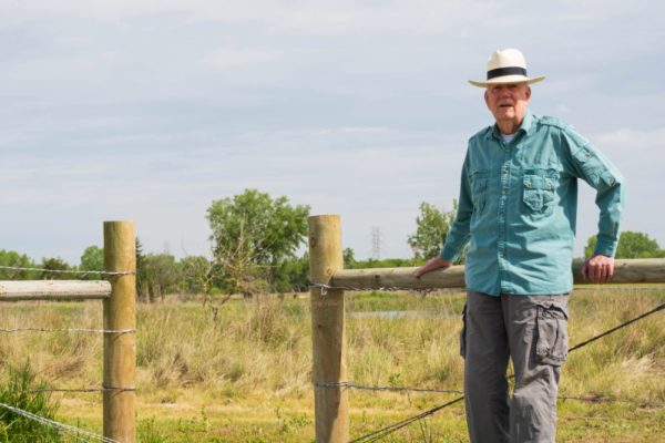 W. Don Nelson leans against a fence by Lincoln's Saline Wetlands.