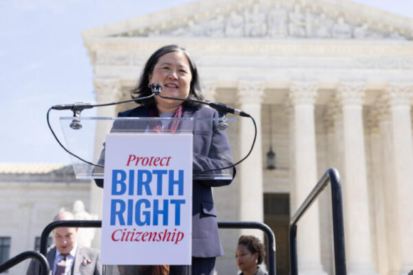 Cecillia Wang is the National Legal Director of the ACLU, in front of the supreme court, behind a podium with a poster reading "Protect Birthright Citizenship"