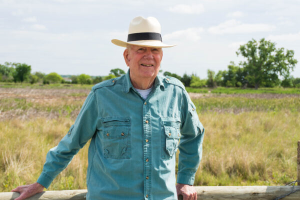 W. Don Nelson leans against a fence by Lincoln's Saline Wetlands.
