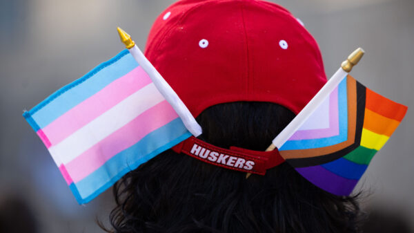 A photo shows someone with a pride and trans pride flag in their Husker hat. Photo by Rebecca Gratz.