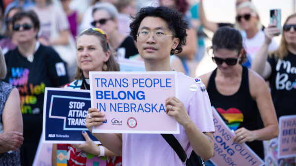 A rally attendee holds a sign reading Trans People Belong in Nebraska.