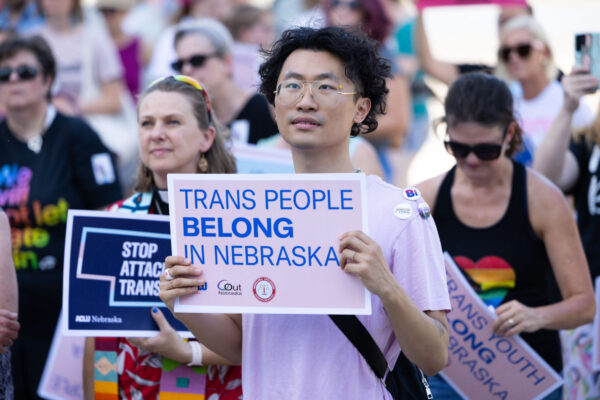 A rally attendee holds a sign reading Trans People Belong in Nebraska.