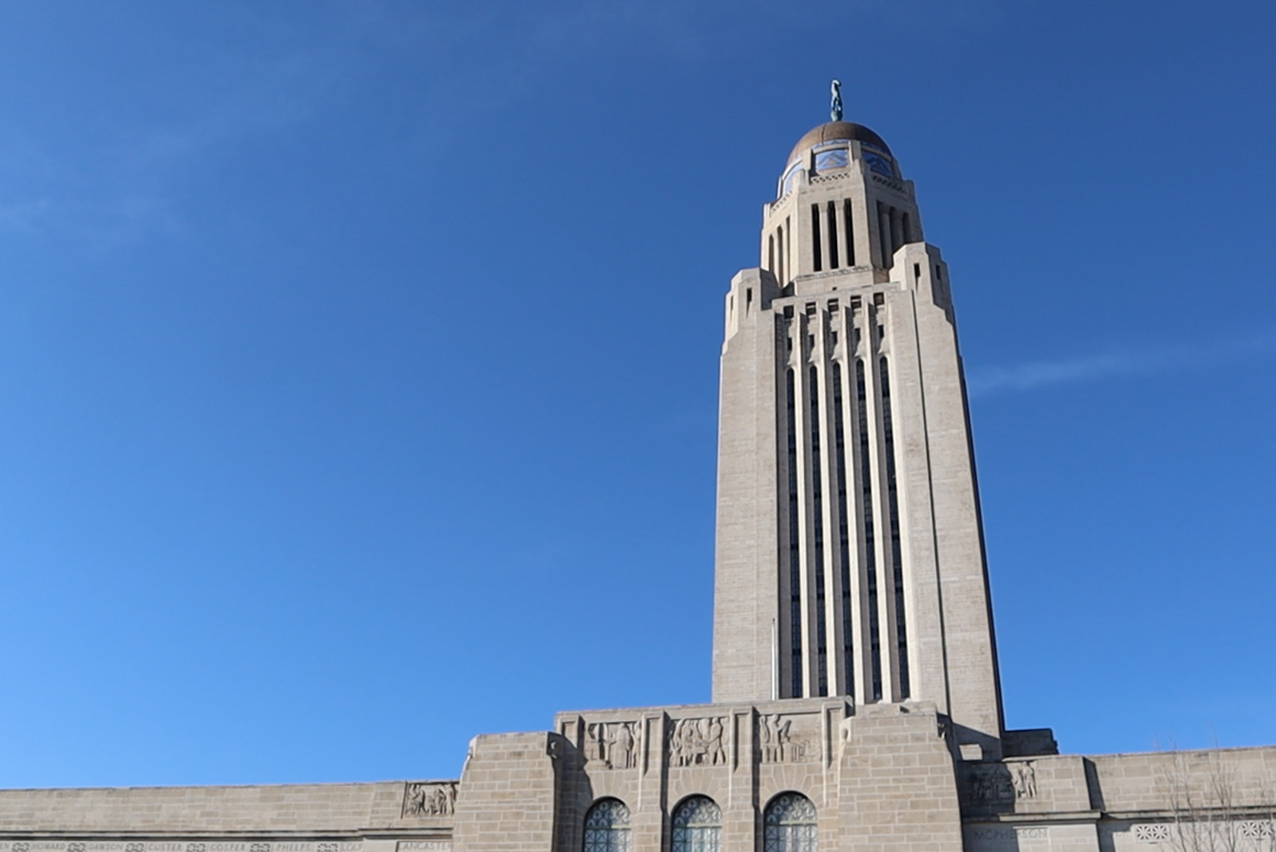 The Nebraska State Capitol stands against a blue sky.