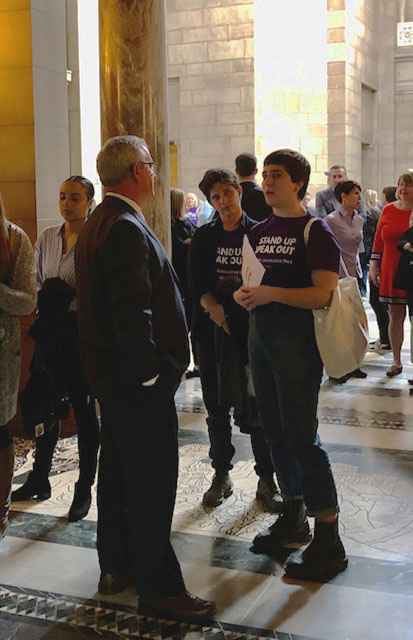 In the background, people are standing in the capitol building rotunda, talking to each other and their state senators. In the foreground, State Senator Dan Hughes and OutNE volunteer Mar Lee talk about LB627 