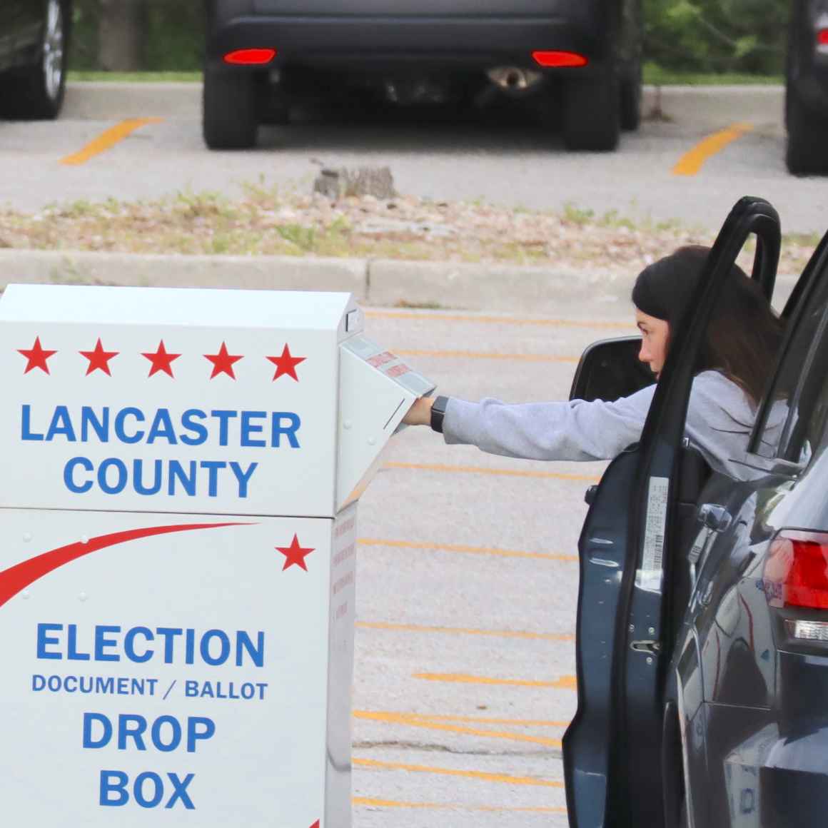 A voter drops a ballot in an election drop box.