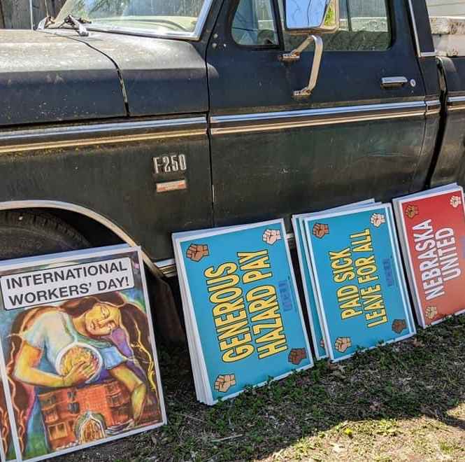 Workers' rights posters lean against a pickup truck.