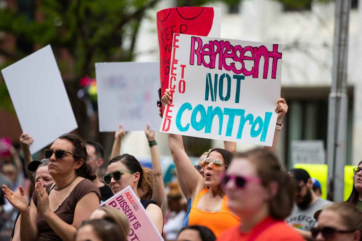 A Nebraskan holds a sign reading "Elected to Represent. Not Control."