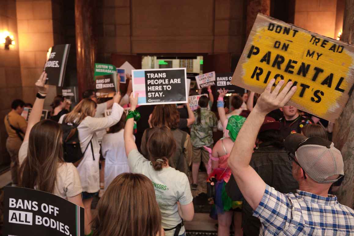 Nebraskans gather to urge senators to reject a bill combing both new restrictions on abortion and on health care for trans youth. One holds a sign reading "Don't tread on my parental rights."