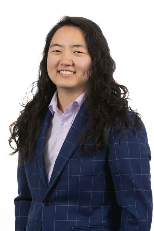 This image of Jane shows a Korean woman with tan skin and long wavy black hair. She is wearing a blue and white windowpane blazer and lavender shirt. 