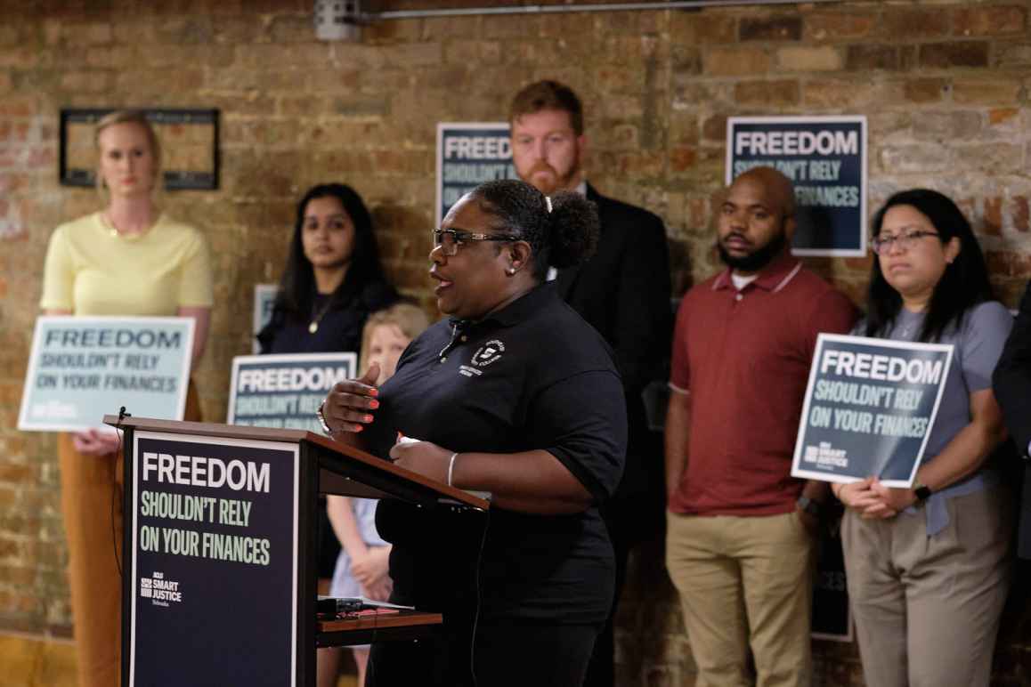 Program volunteer Demetrius Gatson speaks at a podium that reads "Freedom shouldn't rely on your finances."