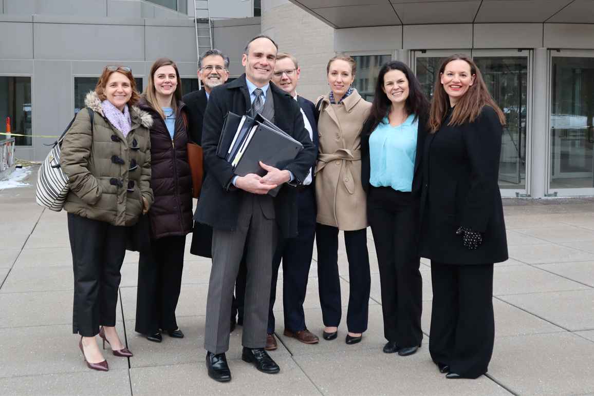 The legal team stands in front of the Roman L. Hruska Federal Courthouse.