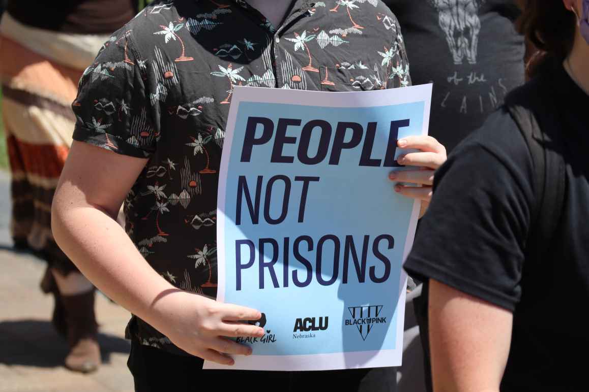 A protester holds a sign reading "People not prisons."