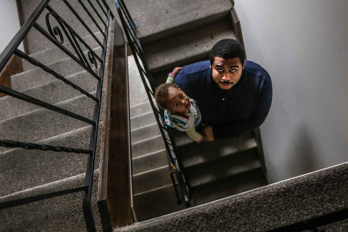 Jacob holding his daughter in the stairwell of their apartment building.