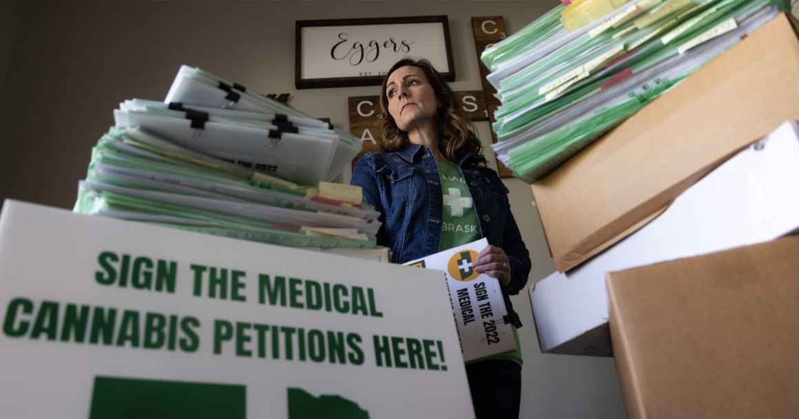 Plaintiff Crista Eggers stands next to collected signatures at her home.