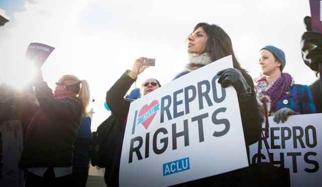 A woman holds a sign reading "I love repro rights."