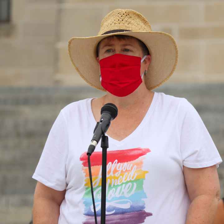 Abbi speaks at a rally outside the Nebraska State Capitol wearing a rainbow shirt that says All You Need is Love.