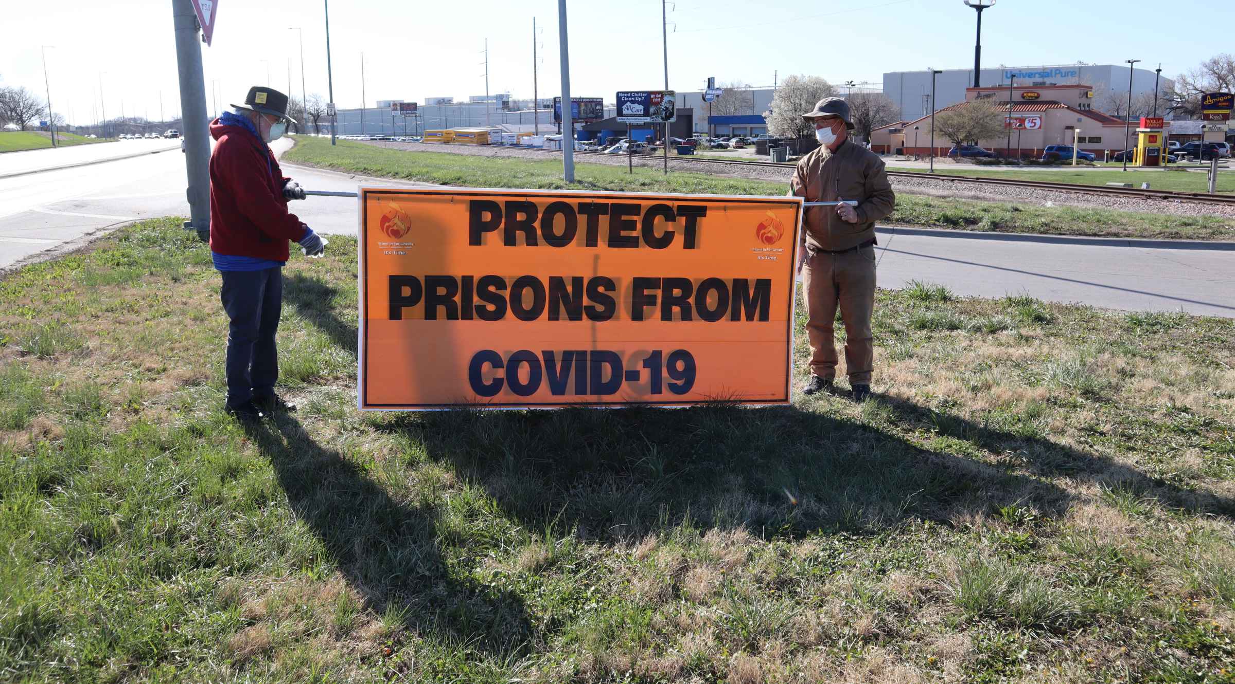 A sign reads "Protect Prisons from COVID-19." A sign reads "Protect Prisons from COVID-19."