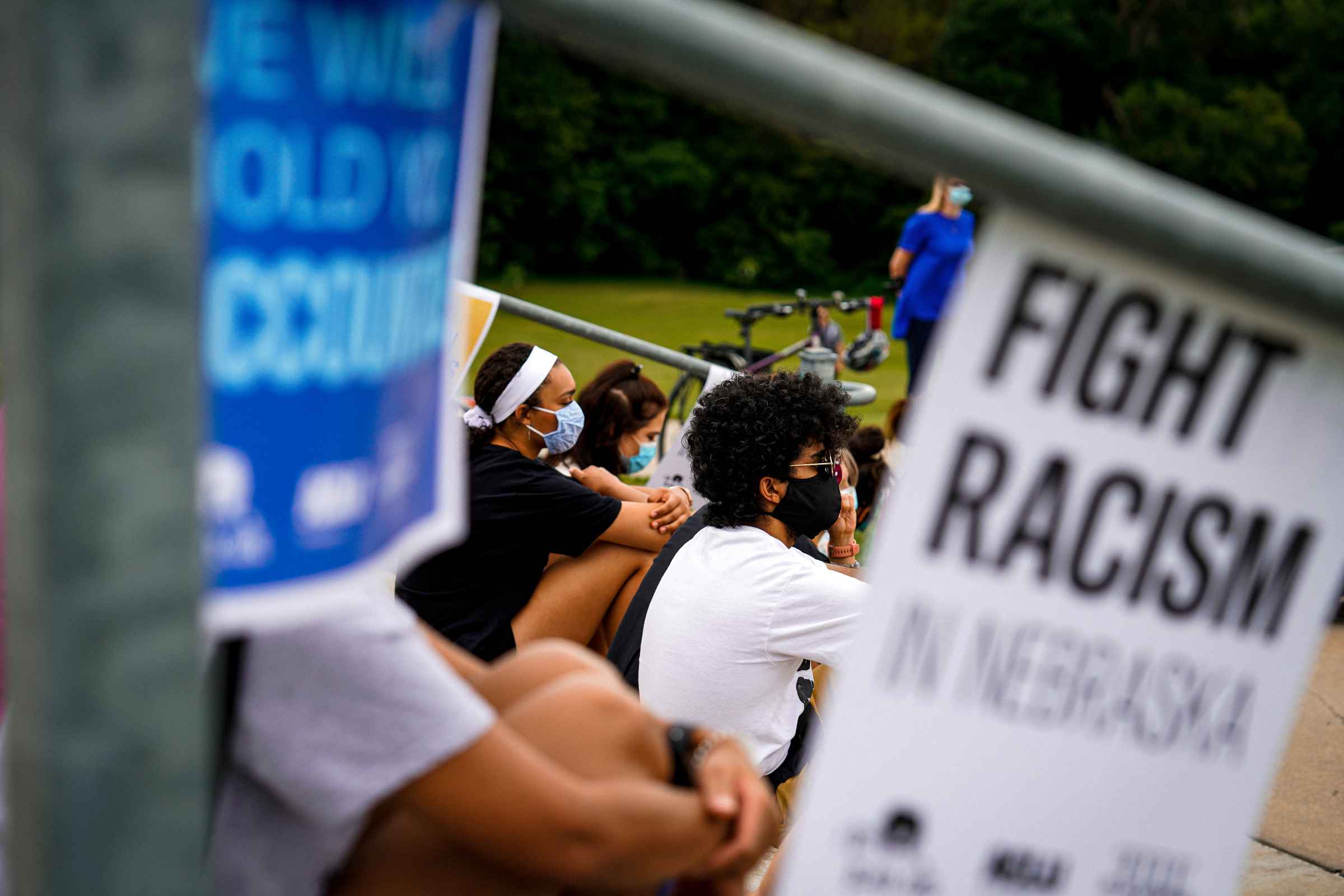 Students sit listening to a speaker at an Educators for Black Lives rally. A sign nearby reads Fight Racism in Nebraska.